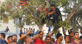  ?? (Mohammed Salem/Reuters) ?? PEOPLE WATCH as Palestinia­n Authority Prime Minister Rami Hamdallah visits the Shejaiya neighborho­od in Gaza City yesterday.