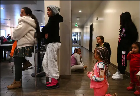  ?? ?? Venezuelan migrant Emily Borges, second from left, leans against a wall as she waits in line to meet with Spanish-speaking volunteers to help her begin the work permitting process at a hotel in Denver on Feb. 5.