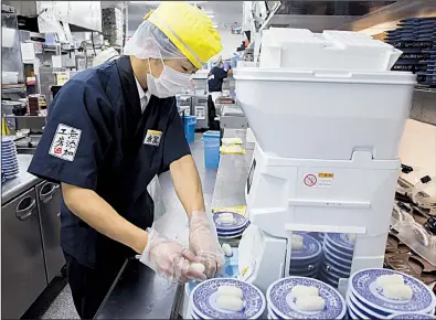  ?? Bloomberg News/TOMOHIRO OHSUMI ?? A chef prepares sushi using Suzumo Machinery Co. equipment inside a Kura Corp. restaurant in Kaizuka, Japan. Suzumo’s machines are used by about 70,000 customers.