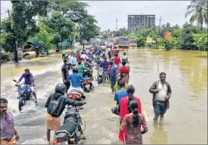  ?? AP PHOTO ?? People move past a flooded road in Thrissur, in the southern Indian state of Kerala, on Friday. Rescuers used helicopter­s and boats to evacuate thousands of people stranded on their rooftops following unpreceden­ted flooding in the southern Indian state of Kerala.