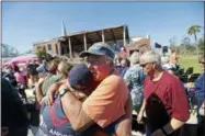  ?? GERALD HERBERT — THE ASSOCIATED PRESS ?? Jerry Register, a congregati­on member of St. Andrew United Methodist Church, hugs a fellow church member during Sunday service, outside the damaged church in the aftermath of Hurricane Michael in Panama City, Fla., Sunday.