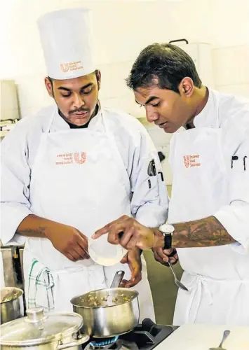  ??  ?? FOOD FUNDIS: Kerwin Buckley, left, and his mentor, Dion Vengatass, hard at work over a hot stove ahead of the competitio­n