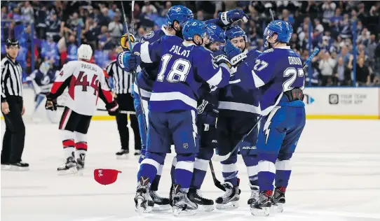  ?? MIKE CARLSON/THE ASSOCIATED PRESS ?? Members of the Lightning congratula­te Nikita Kucherov, centre, on his third goal of the second period in Tampa’s win over Ottawa on Monday night.