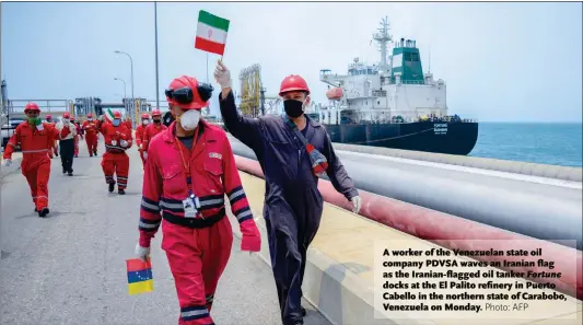  ?? Photo: AFP ?? A worker of the Venezuelan state oil company PDVSA waves an Iranian flag as the Iranian-flagged oil tanker Fortune docks at the El Palito refinery in Puerto Cabello in the northern state of Carabobo, Venezuela on Monday.