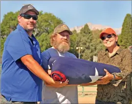  ??  ?? From left, Craig Frechette, branch manager of the local Western Nevada Supply, Andy Boxley, owner of Dean’s Plumbing, pose with the flag with Fair CEO Jen McGuire.