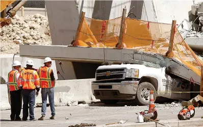  ?? AP Photo/Wilfredo Lee ?? above
Workers stand next to a section of a collapsed pedestrian bridge Friday near Florida Internatio­nal University in the Miami area. The new pedestrian bridge that was under constructi­on collapsed onto a busy Miami highway Thursday afternoon,...