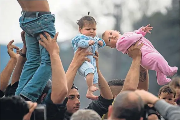  ?? ANDREJ ISAKOVIC / AFP ?? Un grupo de refugiados muestra a sus hijos durante una acción de protesta contra el cierre de la frontera greco-macedonia en Idomeni