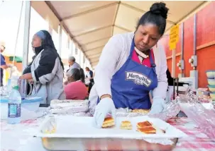  ?? STAFF PHOTO BY ERIN O. SMITH ?? Nicole Walker with the House of God Church places cornbread in a pan at the 22nd annual National Cornbread Festival in 2018.