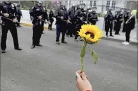  ?? Luis Sinco Los Angeles Times ?? A PROTESTER offers a flower to officers during a rally over the Echo Park camp closure last month. The LAPD made over 180 arrests the second night of protests.