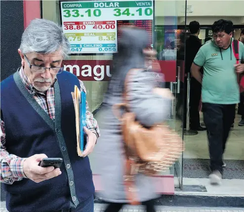  ?? EITAN ABRAMOVICH / AFP / GETTY IMAGES FILES ?? Currency exchange values at a bureau de exchange in Buenos Aires last month. Argentina’s President Mauricio Macri said Wednesday the IMF has agreed to accelerate funding in support of his government’s austerity program.