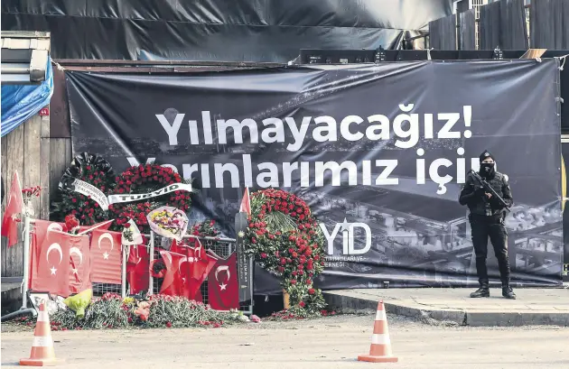  ??  ?? A police officer stands guard outside the Reina nightclub against the backdrop of a banner that reads in Turkish, “We will not give up! For our tomorrow,” Jan. 3, 2017.