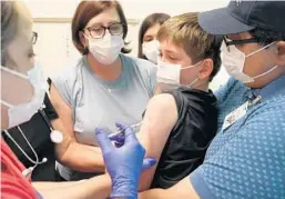  ?? ANTONIO PEREZ/CHICAGO TRIBUNE ?? Gabriel Gometz, 8, is held by his his parents, Shannon Lightner-Gometz and Edward Gometz, while his sister, Juliana, 11, looks on as Erica Ruvalcaba administer­s a COVID-19 vaccine at Lurie Children’s Hospital in Chicago.