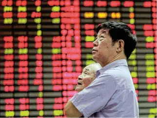  ?? Reuters ?? In the red: Two men stand at an electronic stock board in Shanghai in this file photo. More than 400 investment bankers have lost their jobs in Hong Kong alone — most of them focused on Chinese deals. /