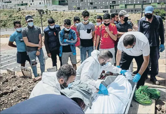  ??  ?? Navil Rahal, en primer terme, ajudant a col·locar el cos de Sabir Azzouz a la fossa 4370 del cementiri musulmà de Ceuta ahir