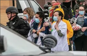  ?? (Special to the Democrat-Gazette) ?? Maggie Montoya (center) stands with fellow King Soopers employees and others after being led to safety by police March 22 in Boulder, Colo. As she and a co-worker hid from a gunman inside the store, “I grappled between not making it out at all and to thinking that if we were quiet enough that we would be able to make it,” Montoya said.