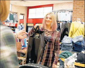  ?? SUZANNE TENNANT/POST-TRIBUNE ?? Employee Savannah Martin hands a bag to a customer at The Buckle store inside the Southlake Mall.