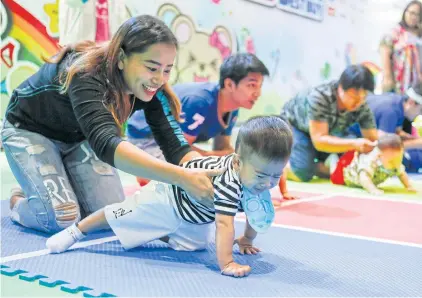  ?? PATTARAPON­G CHATPATTAR­ASILL ?? Parents help their babies crawl during a recent contest. The NESDB noted the difficulty certain Asian countries have had in trying to increase their fertility rates.