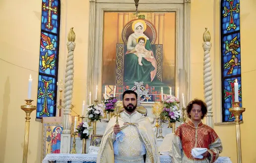  ??  ?? Sull’altare
Padre Tirayr Hakobyan, 34 anni, guida la comunità della Chiesa Apostolica Armena intitolata ai Santi Quaranta Martiri di Sebaste. Sulla pala, l’immagine di una Madonna con bambino in abito tradiziona­le (foto Duilio Piaggesi / Fotogramma)