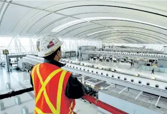  ?? THE CANADIAN PRESS FILES ?? An Aecon Constructi­on scissor lift operator looks at Toronto Pearson Internatio­nal Airport’s new Terminal 1 check-in area on Dec. 2, 2003. The Trudeau Liberals are facing warnings to proceed cautiously and in as transparen­t a manner as possible as it...