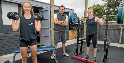  ?? MURRAY WILSON/STUFF ?? Weightlift­ers Shelby Wells, left, and Sam Hansen, right, with coach Shayne Nation at the weightlift­ing area he has built in his back yard.