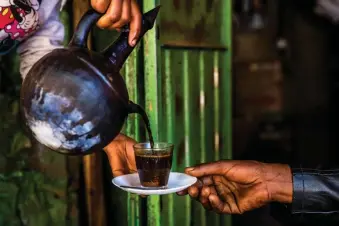  ??  ?? A WOMAN serves coffee from a jebena, a traditiona­l Ethiopian coffee pot, in one of the markets of Harar Jugol, Ethiopia. Old Harar is designed to intoxicate the senses, with spice markets, food stalls and a kaleidosco­pic bustle of people. | The New York Times