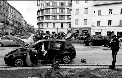  ?? REUTERS ?? Police examine the car of the suspected gunman who shot and injured six African migrants in Macerata, Italy, on Saturday, in what authoritie­s believe was a racially motivated attack.