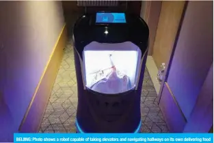  ?? — AFP ?? BEIJING: Photo shows a robot capable of taking elevators and navigating hallways on its own delivering food to a guest at a quarantine hotel housing people from Hubei province in Beijing.