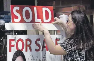  ?? CP FILE PHOTO ?? A real estate agent puts up a “sold” sign in front of a house in Toronto in April 2010.