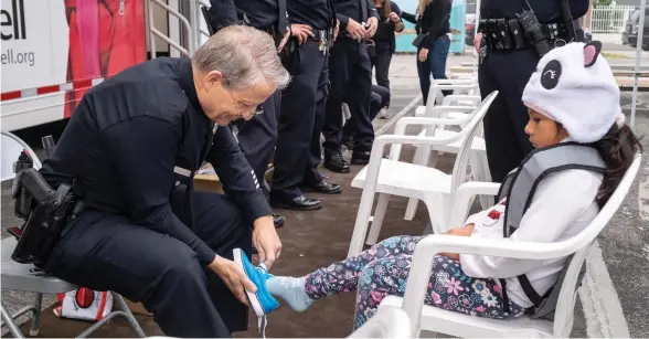  ?? / FOTO DE ISAAC CEJA ?? Un agente le coloca unos tenis nuevos a una alumna de la escuela Bassett Street Elementary School en Los Angeles.