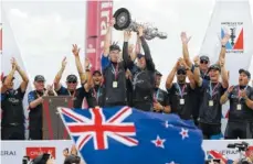  ?? THE ASSOCIATED PRESS ?? Emirates Team New Zealand helmsman Peter Burling, left, and teammate Glenn Ashby hold the America’s Cup aloft as they celebrate with teammates after defeating Oracle Team USA in the sailing competitio­n Monday in Hamilton, Bermuda.