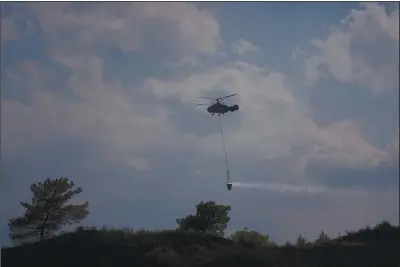  ??  ?? A helicopter flies over the burned Larnaca mountain region Sunday near the village of Ora in Cyprus.