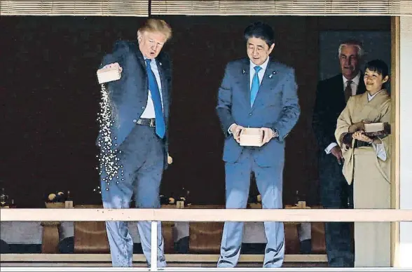  ?? TORU HANOI / AP ?? Impaciente, Trump vierte todo el contenido de la caja en el ritual de alimentaci­ón de las carpas koï ante la mirada de Shinzo Abe
