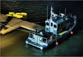 ?? ANDRES KUDACKI — THE ASSOCIATED PRESS ?? Yellow buoys that a New York police officer said are suspending a helicopter that crashed into the East River float next to a NYPD police boat at a pier in New York on Sunday. The helicopter crashed into New York City’s East River Sunday night and...