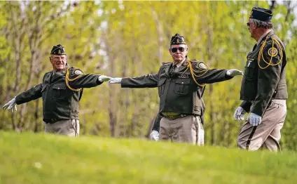  ?? Alex Kormann / Associated Press ?? Members of the Duluth honor guard stretch out their arms to ensure they stood 6 feet apart for social distancing during the modified Memorial Day service at Forest Hill Cemetery in Duluth, Minn.