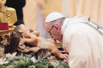  ?? ANDREW MEDICHINI/ASSOCIATED PRESS ?? Pope Francis kisses a statue of the Divine Infant as he arrives to celebrate an Epiphany Mass in St. Peter’s Basilica in the Vatican on Saturday.