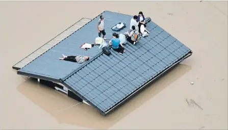  ?? SHINGO NISHIZUME/KYODO NEWS VIA AP THE ASSOCIATED PRESS ?? People wait to be rescued on the top of a house almost submerged in flood waters caused by heavy rains in Kurashiki, Okayama prefecture, Japan. Torrential rains continued to batter parts of western Japan on Sunday