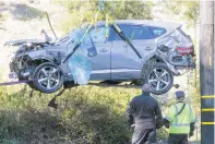  ?? RINGO HW CHIU/ASSOCIATED PRESS ?? A crane is used to lift a Genesis SUV that Tiger Woods was driving when it crashed on Tuesday in Los Angeles. Woods suffered leg injuries and was undergoing surgery.