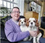  ?? — AFP ?? Parish Priest Father Ray Kelly, know also as “Ireland's Singing Priest,” poses for a photograph with his dogs Biddy and Buddy, in his home in Oldcastle, north Ireland, on April 19, 2015. Twelve months ago, Kelly sang a version of Leonard Cohen's...