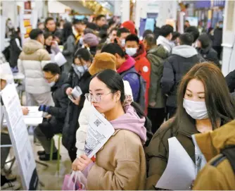  ?? AP-Yonhap ?? Chinese jobseekers hold brochures as they search for job vacancies at a job fair in Beijing, Feb. 23. Despite multiple relocation obstacles, more Chinese mainlander­s are seeking jobs in Hong Kong through the Top Talent Pass Scheme launched in December 2022.