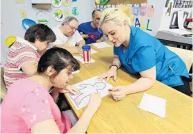  ?? RICARDO RAMIREZ BUXEDA/STAFF PHOTOGRAPH­ER ?? Amy colors with the aid of Ashley Blair at the Russell Home for Atypical Children. The facility houses children and adults with brain injuries. Video: OrlandoSen­tinel.com.