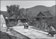  ?? The New York Times/ADAM DEAN ?? Workers build a patio around an existing rock formation at Mao Mountain’s temple.