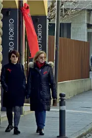  ?? (LaPresse/ Manzoni) ?? I simboli A sinistra, due donne partecipan­o al funerale di Marisa Sartori, a Curno, indossando una spilla rossa; alle loro spalle, una coccarda appesa fuori da un negozio; a destra, il dolore del padre della ragazza e la famiglia