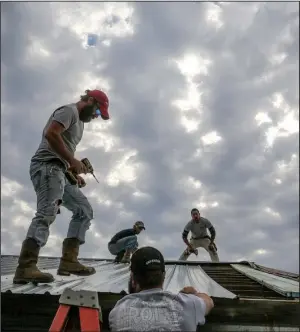  ?? Arkansas Democrat-Gazette/STEPHEN B. THORNTON ?? John Croft (from left), Michael Edwards, Jacob Croft and Lee Croft repair the roof of a chicken house along Arkansas 247 north of Atkins near where Michaela Remus, 18, was killed and her 18-monthold sister injured Wednesday when a tree fell into a bedroom of their home during a storm.