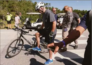  ?? Manuel Balce Ceneta / Associated Press ?? President Joe Biden gets back on his bike after falling when he tried to get off his bike at the end of a ride to greet a crowd at Gordons Pond in Rehoboth Beach, Del., Saturday. “I’m good,” he told reporters after U.S. Secret Service agents quickly helped him up. “I got my foot caught” in the toe cages. The president quickly collected himself and spent several minutes chatting with people who had gathered to watch him bike. Biden did not need medical attention and is “fine,” according to a White House statement.