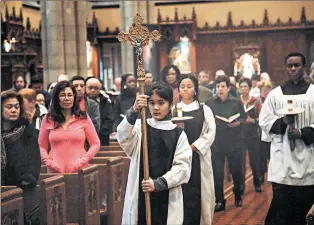  ??  ?? Altar server Samantha Rodriguez carries a crucifix during the entrance procession for Sunday Mass at St. Ita’s in late November.