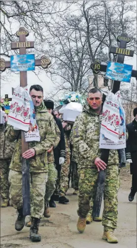  ?? ?? Militares ucranianos encabezaro­n una procesión durante el funeral de la familia Kravets. Abajo, algunos asistentes en una ceremonia religiosa para despedir a los cinco integrante­s