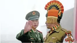  ??  ?? SIKKIM: This file photo shows a Chinese soldier, left, gesturing next to an Indian soldier at the Nathu La border crossing between India and China in India’s northeaste­rn Sikkim state. — AFP