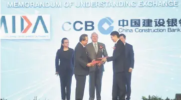  ??  ?? Najib (centre) witnessing the exchange of documents between representa­tives from MIDA and CCBM of China after officiatin­g at the opening of CCBM. — Bernama photo