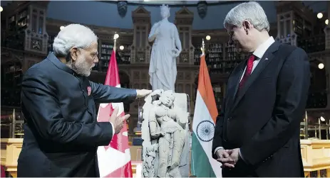  ?? Adrian Wyld / The Cana dian Press ?? Then-prime minister Stephen Harper returns a sculpture of a woman known as the “Parrot Lady” to Indian Prime Minister Narendra Modi in the Parliament­ary Library on Parliament Hill in April.