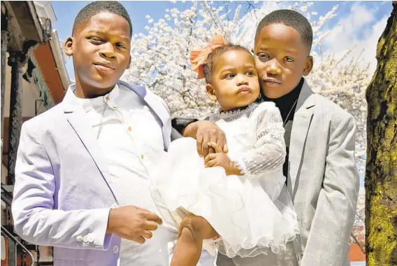  ?? AMY DAVIS/BALTIMORE SUN PHOTOS ?? Dressed in their Easter best, twin brothers Dominique, left, and Da’yonne Myers, holding their sister, J’Lynn Myers, pose for family pictures after church.